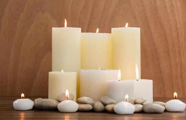 White candles and pebbles stone on wood in spa center