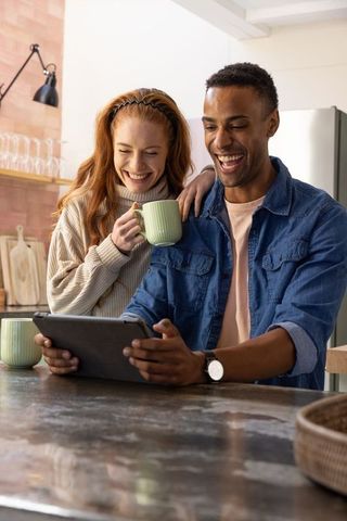 Cheerful Couple Relaxing with Tablet in Modern Kitchen