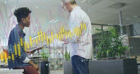 Young professionals collaborating over tablet with financial analytics overlay in office