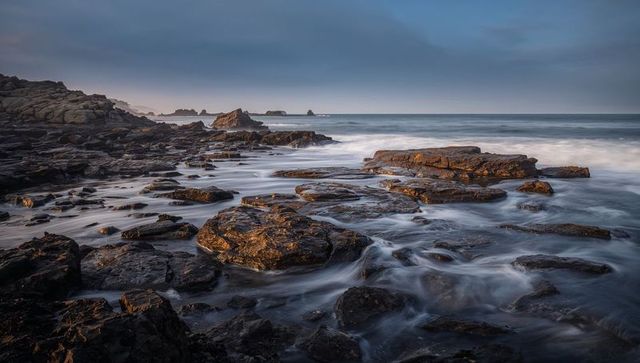 Jagged tidal platform glistening at low tide with flowing water and rock pools