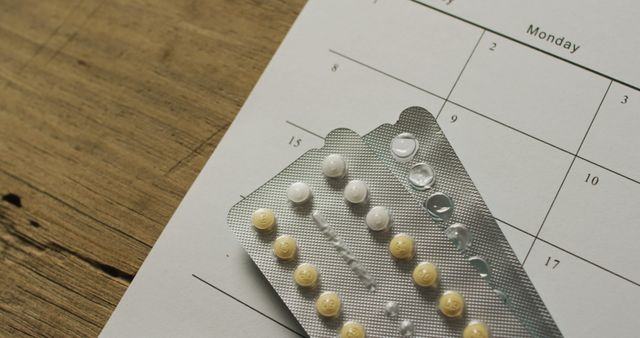 Image of close up of yellow tablets over calendar on wooden table. global medicine and healthcare concept.