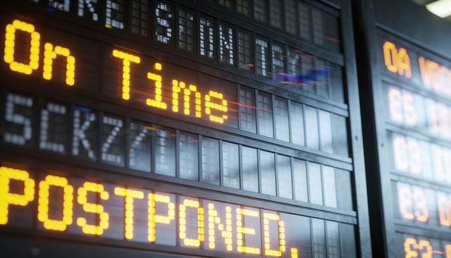 Departure board displaying on time and postponed amber led timetable at transport station