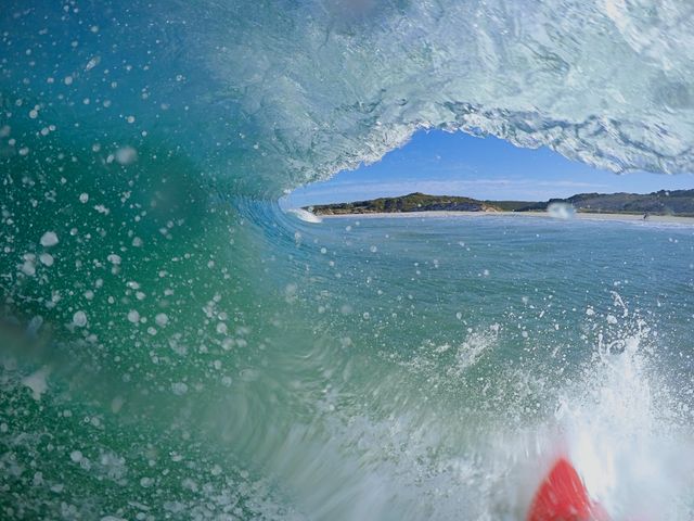 Ocean wave curling to create tunnel offering surfer's perspective. Ideal for illustrations on surfing lifestyle, water sports, extreme adventures, summer activities, beach retreats.