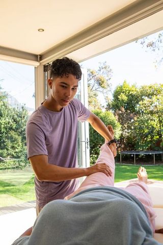 Therapist Stretching Senior's Leg During Outdoor Rehabilitation Session