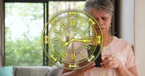 Senior woman holding smartphone viewing golden augmented reality clock overlay at home