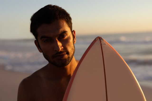 Portrait of man standing with surfboard on the beach