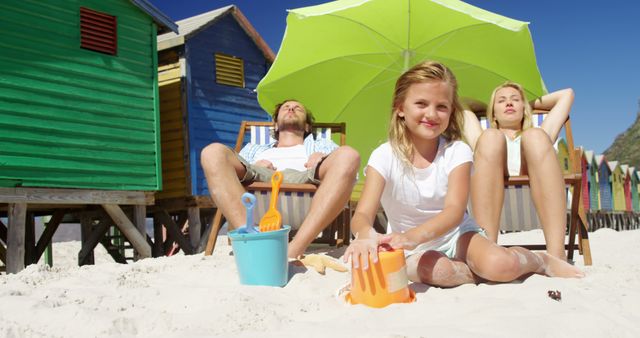 Family Relaxing at Beach in Front of Colorful Beach Huts - Download Free Stock Images Pikwizard.com