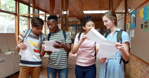 Diverse group of teenagers discussing exam results in school hallway
