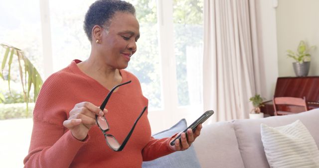 Senior Woman Using Smartphone and Holding Glasses in Cozy Living Room - Download Free Stock Images Pikwizard.com