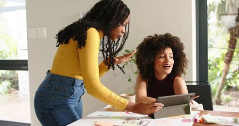 Diverse colleagues collaborating over tablet, brainstorming creative ideas in bright office