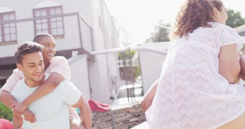 Happy Couples Enjoy Piggyback Ride in Sunny Garden Party