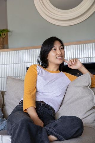 Asian american woman relaxing on modern sofa in cozy living room