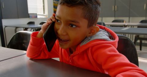 Smiling Schoolboy Talking on Mobile Phone in Classroom
