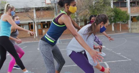 Female basketball team playing outdoors with face masks
