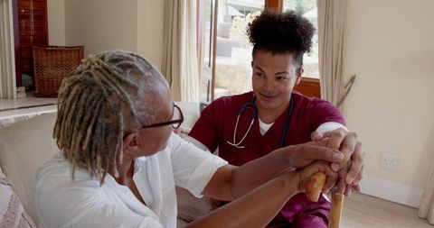 Male Nurse Comforting Senior Woman With Cane in Domestic Setting