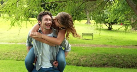 Joyful Couple Enjoying Piggyback Ride in Lush Park