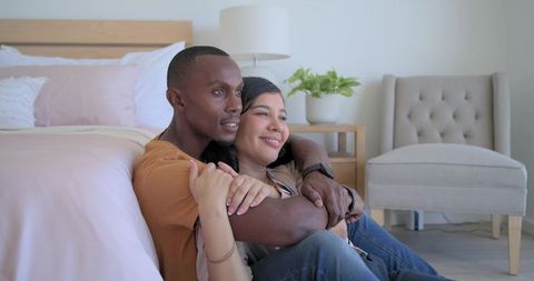 Couple embracing on bedroom floor sharing cozy morning emotions and home intimacy