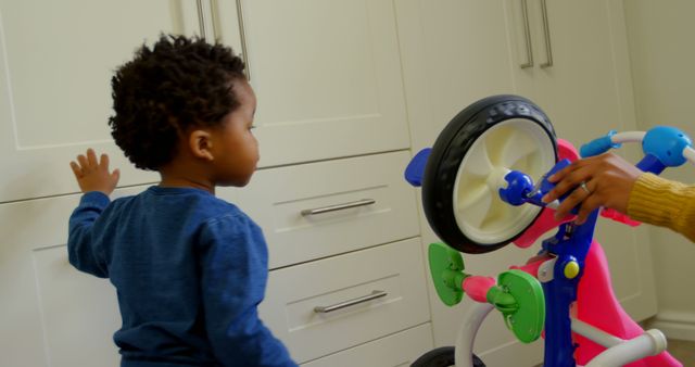 Toddler Curiously Exploring Colorful Tricycle Indoors - Download Free Stock Images Pikwizard.com