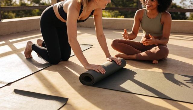 Rooftop women rolling yoga mats and chatting in morning sunlight