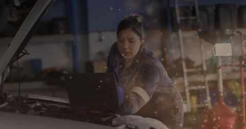 Female mechanic diagnosing engine with laptop in auto garage