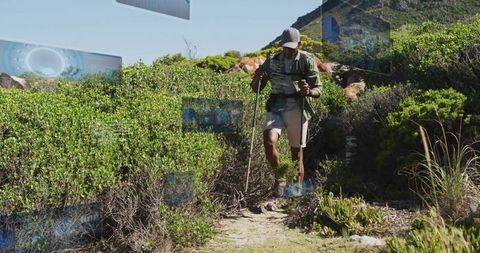 Male hiker navigating narrow coastal trail with backpack and trekking poles