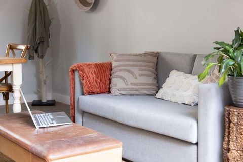 Minimalist living room featuring light gray sofa, textured pillows and rust throw