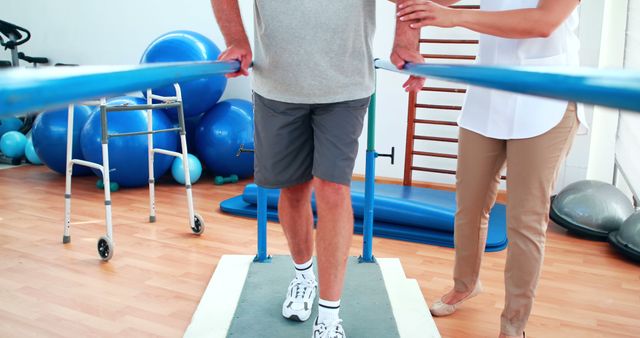 Elderly man receiving assistance and guidance from physiotherapist for rehabilitation. Useful for articles or promotions about physical rehabilitation, elderly care, medical and healthcare services.