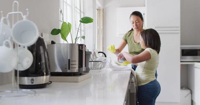 Image of happy asian mother and daughter cleaning kitchen. Family, motherhood, relations and spending quality time together concept digitally generated image.