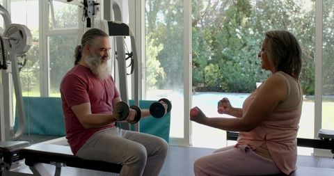 Senior couple engaging in fitness routine with dumbbells at home gym