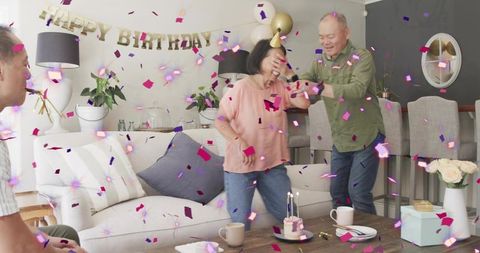Senior Couple Celebrating Joyful At-Home Birthday Party with Confetti, Balloons, Cake and Gifts