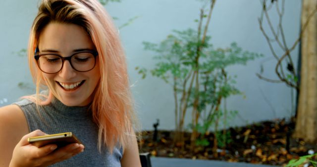 Young Woman with Pink Hair Smiling While Using a Smartphone Outdoors - Download Free Stock Images Pikwizard.com