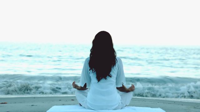 Representation of a woman sitting in meditation by the sea. Apt for promoting wellness, mindfulness retreats, holistic health practices, or stress-relief seminars. Perfect for illustrating concepts around inner peace and self-care.