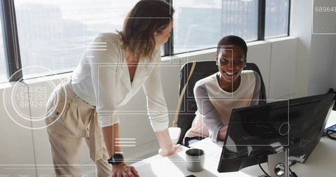 Two Women Collaborating in Modern Office with Cityscape View