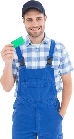 young repairman in blue overalls smiling while holding green card. useful for service advertisements, websites promoting repair or maintenance services, and customer service branding highlighting friendly staff.