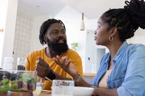 African american couple discussing over salad at bright modern kitchen table