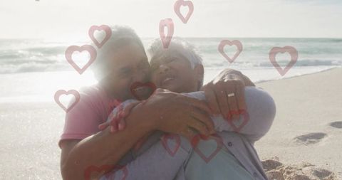 Senior Couple Embracing on Beach with Romantic Hearts Overlay