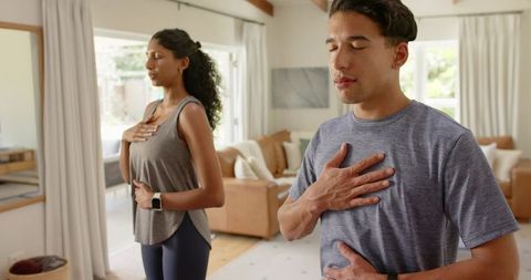 Couple practicing breathwork and mindful breathing in sunlit living room