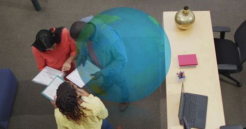 Top-down business team collaborating around documents with overlaid globe graphic