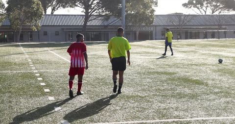 Soccer referee and players walking on field during training session