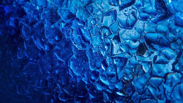 Shattered cobalt glass reflecting light macro abstract texture with droplets