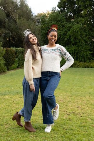 Friends posing and smiling in garden wearing festive headbands and cozy knit sweaters