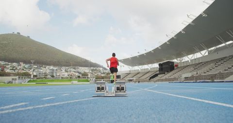 Male Athlete Running Alone on Outdoor Track under Blue Sky