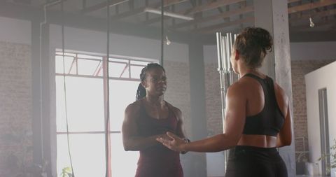 Two women discussing workout routine in modern gym