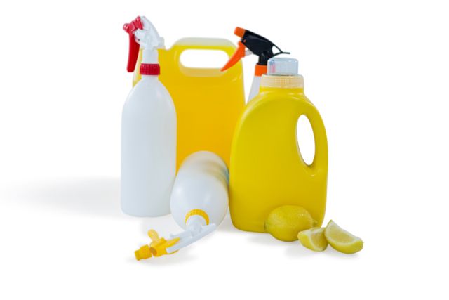 Cleaning liquid bottles with lemon against white background