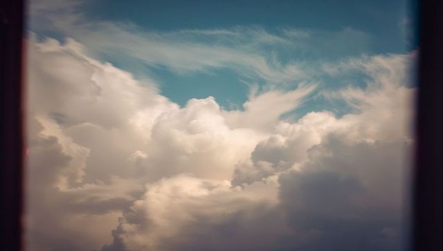 Serene puffy clouds viewed through open window frame