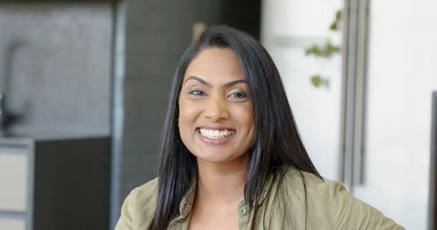 Smiling Indian professional woman sitting at modern office reception with soft lighting