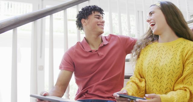 Two Friends Laughing and Using Tablets on Stairs - Download Free Stock Images Pikwizard.com