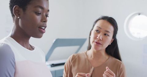 Two diverse businesswomen collaborating in modern office environment