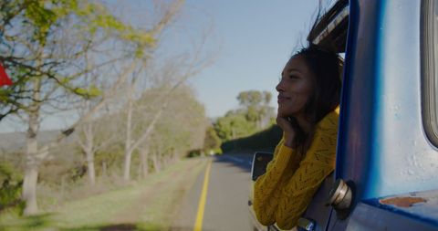 Young Woman Enjoys Scenic Road Trip from Car Window