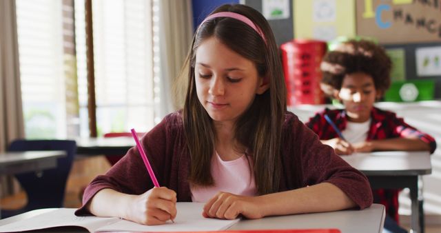 Focused Schoolgirl Writing Notes in Classroom Environment - Download Free Stock Images Pikwizard.com